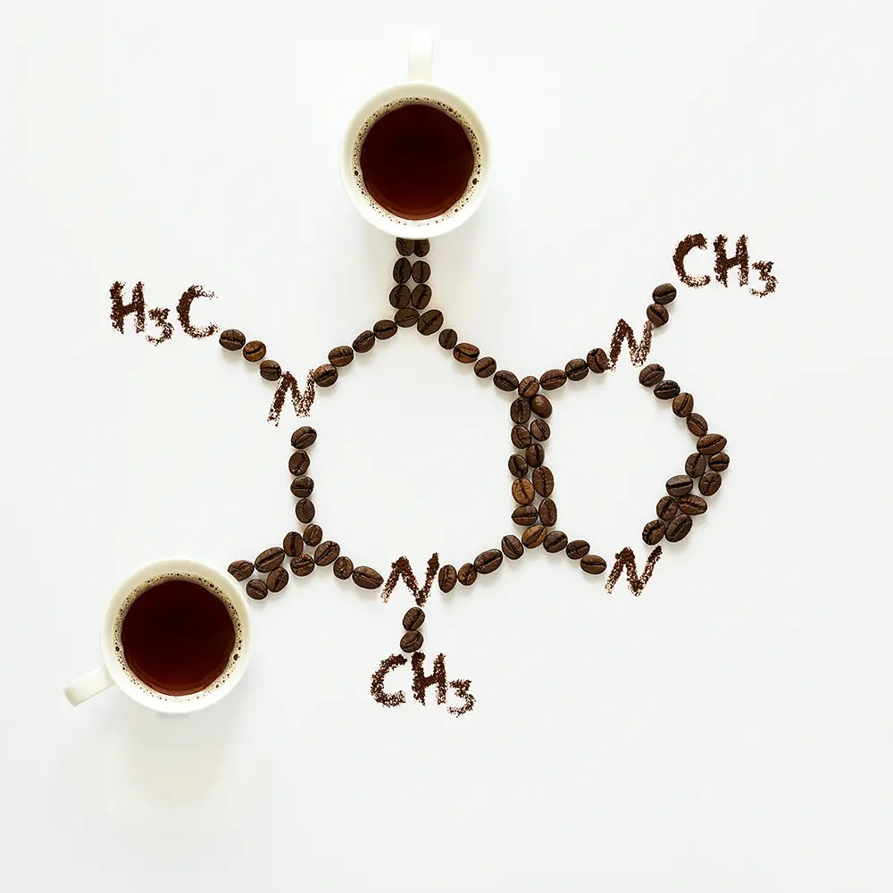 coffee cups of coffee and coffee beans arranged in the shape of a caffeine molecule