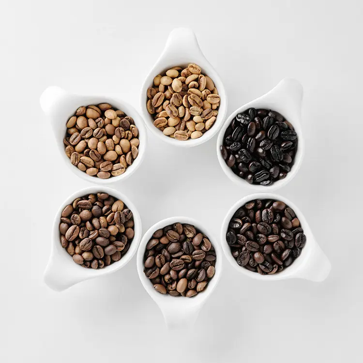 a group of coffee beans at different roast levels and colors in white cups